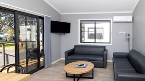 Ein modernes Wohnzimmer mit einer Couch, einem Couchtisch und einem an der Wand befestigten Fernseher.