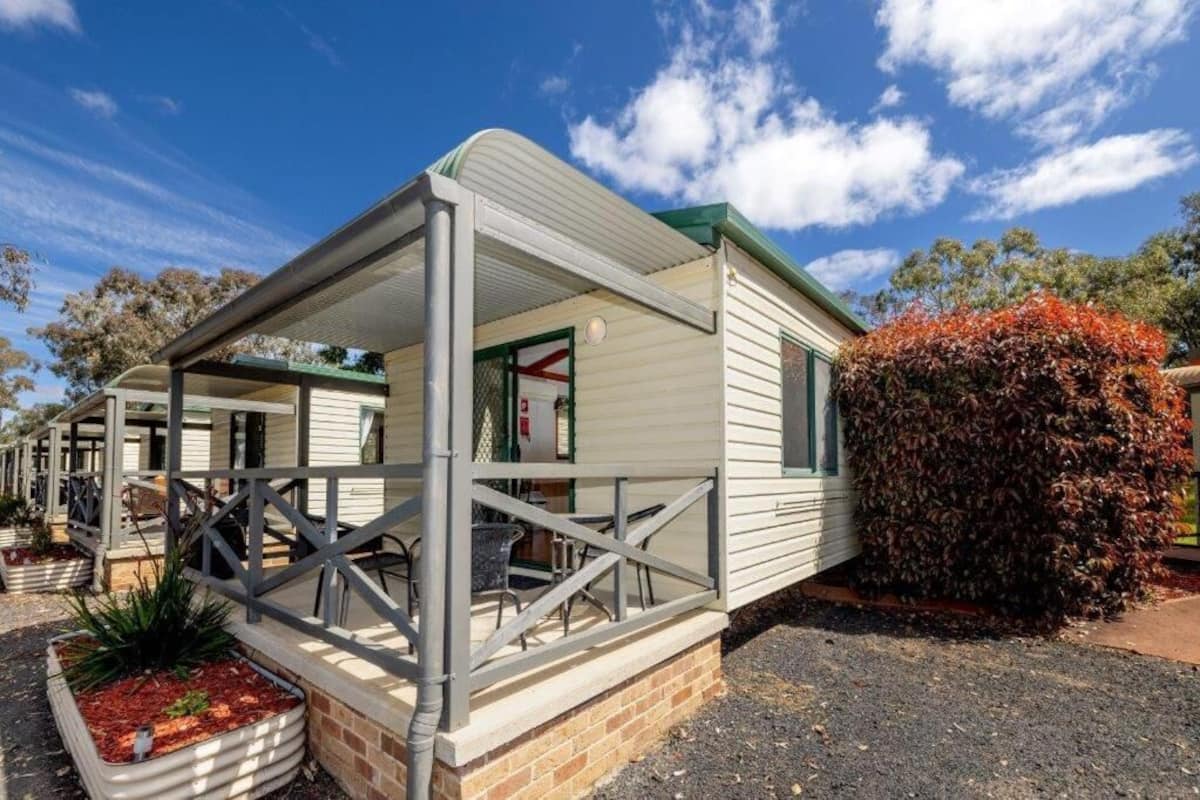 A caravan with a covered porch and outdoor seating area.