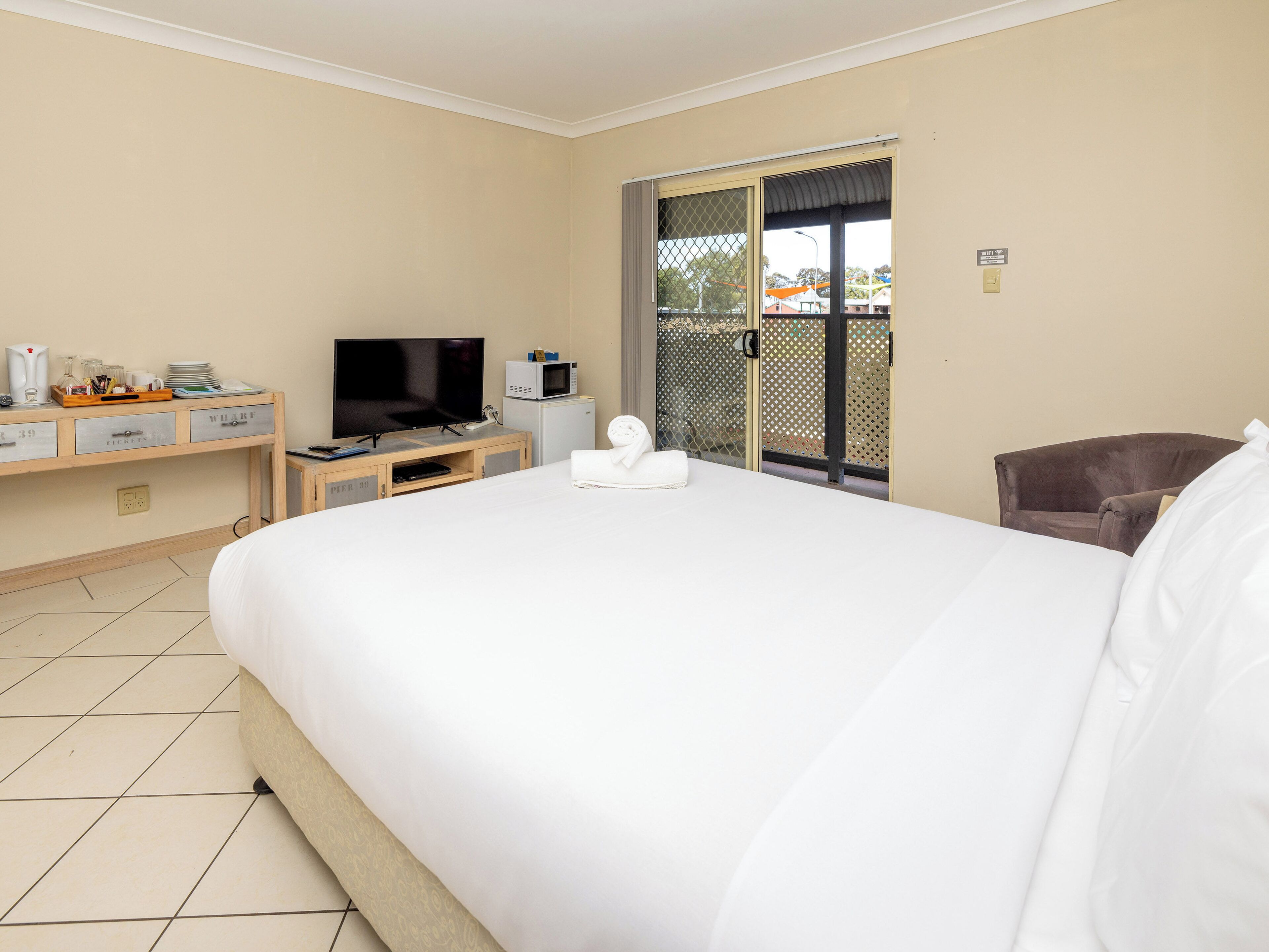 Ein Hotelzimmer mit einem Bett, einem Fernseher, einem Schreibtisch mit Computer, einer Mikrowelle und einem kleinen Kühlschrank.