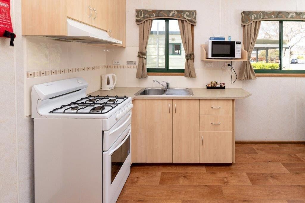 A compact kitchen with a gas stove, a microwave, and a sink.