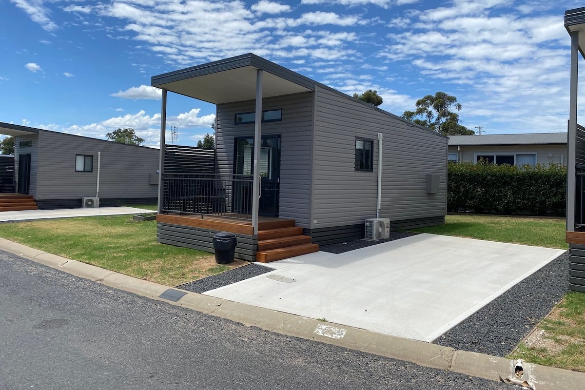 A modern single-story mobile home with a covered porch and a small front yard.