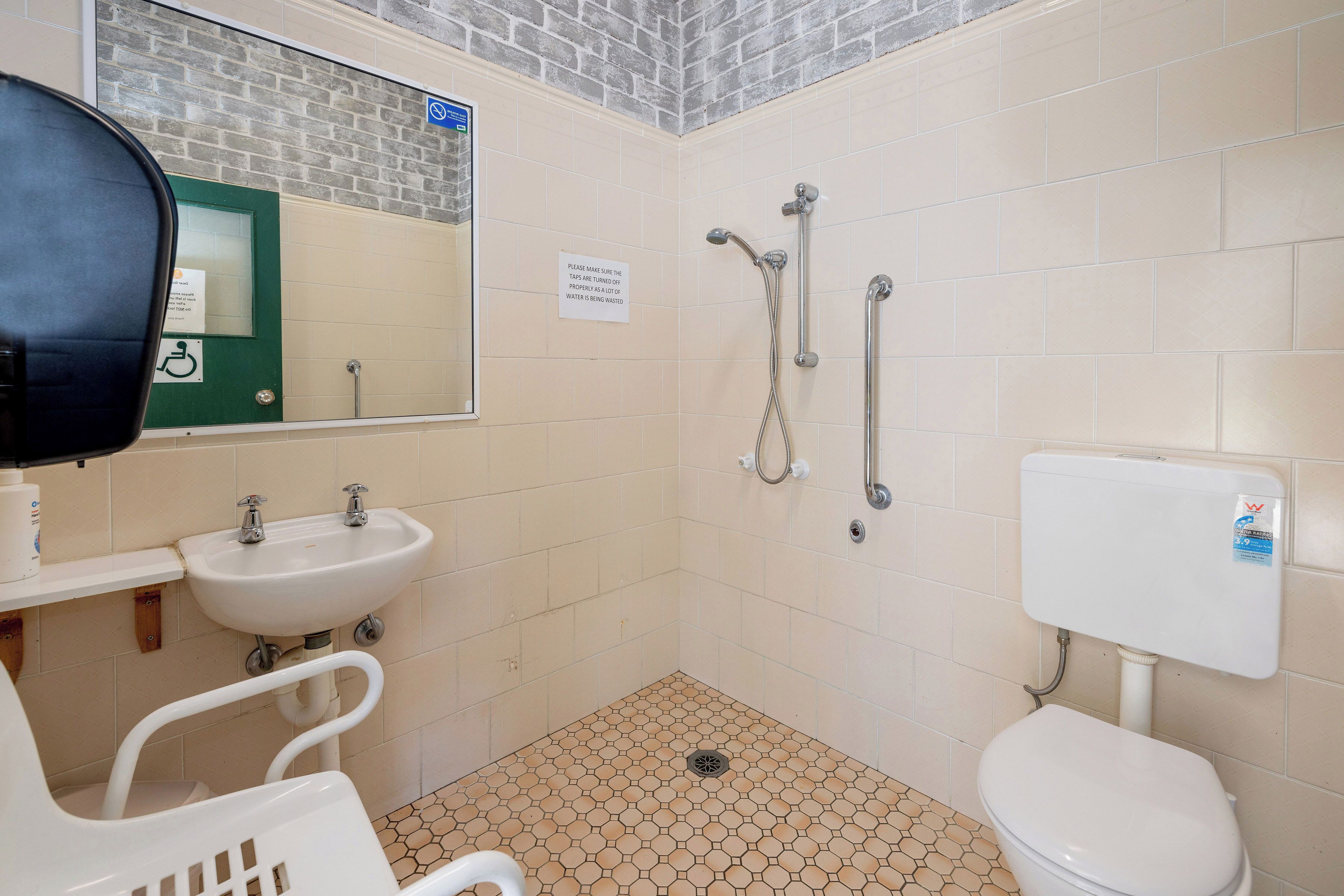 Et lille badeværelse med toilet, håndvask og brusebad.