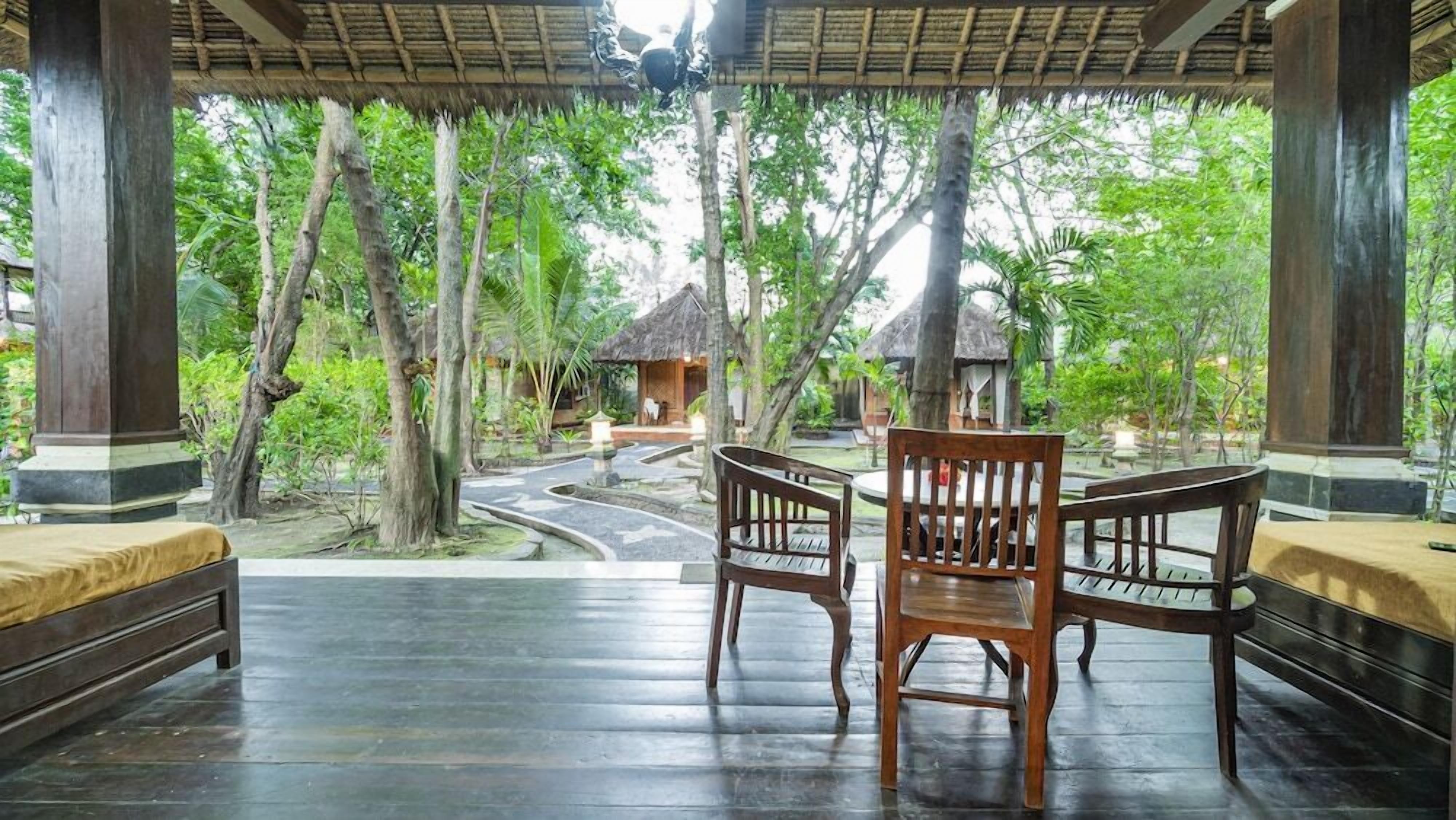 A covered outdoor seating area with wooden benches and a view of a garden.