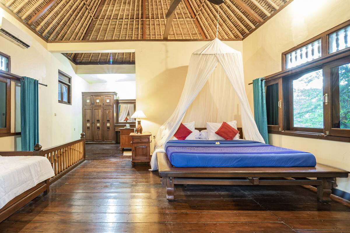 A room with a bed, a nightstand, a wooden wardrobe, and a window with a view.