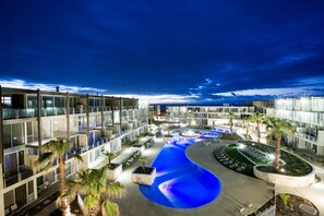 A modern hotel with a swimming pool, palm trees, and a well-lit outdoor area. - Onshore Torquay (Torquay)