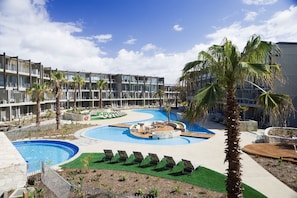 Een hotel met een zwembad, palmbomen en een zonneterras.
