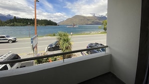 A balcony with a view of a lake, a boat, and mountains in the background. - Lakeside Motel - Queenstown (Queenstown)