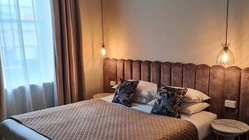 Una cama bien hecha con un edredón marrón, dos almohadas y una mesita de noche con una lámpara.