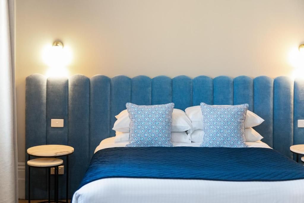 A hotel room with a large bed, two bedside tables, and a blue headboard.