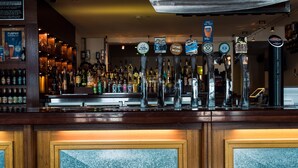 A bar with multiple beer taps and a variety of liquor bottles.