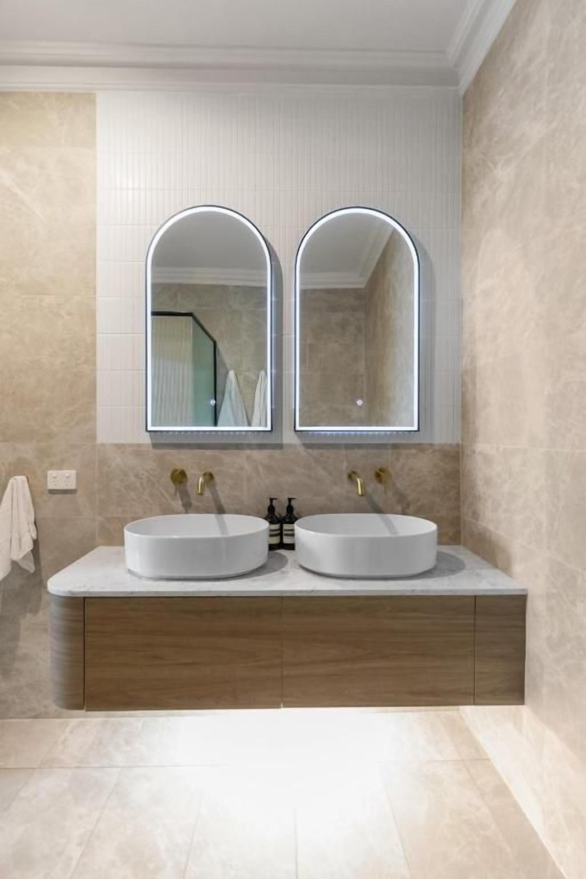 Un baño con dos lavamanos, un espejo y un mueble de madera.