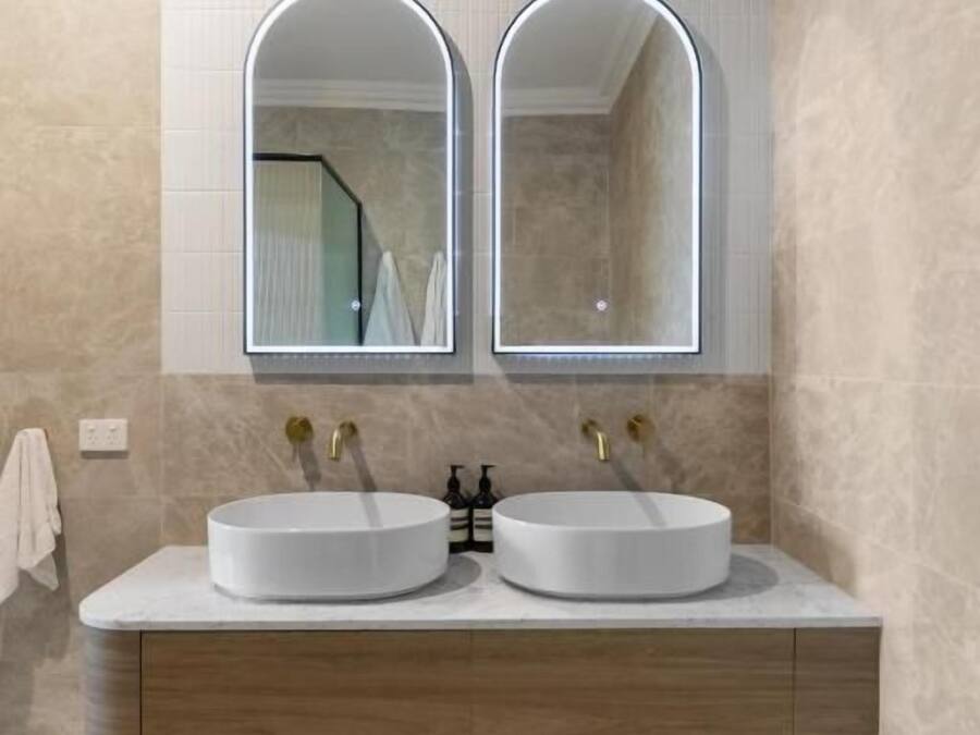 Un baño con dos lavamanos, un espejo y un mueble de madera.
