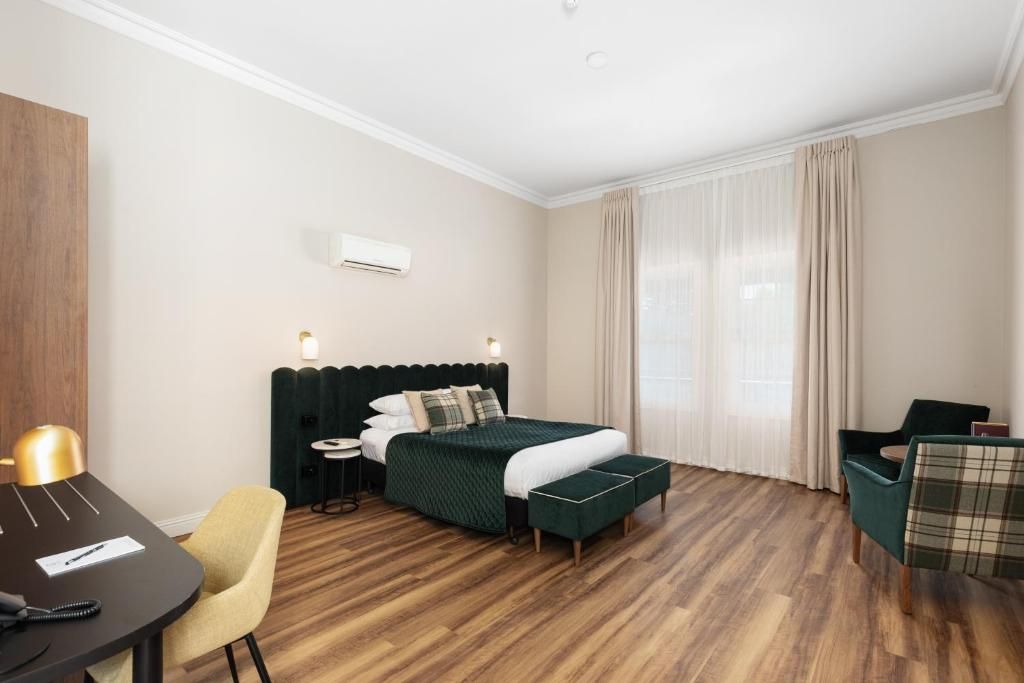 Ein Hotelzimmer mit Bett, Schreibtisch, Stuhl und einem kleinen Tisch.