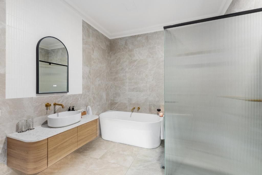 Un baño moderno con una bañera independiente, un tocador con lavamanos y una cabina de ducha con mampara de vidrio.