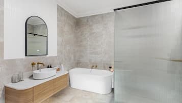 Un baño moderno con una bañera independiente, un tocador con lavamanos y una cabina de ducha con mampara de vidrio.