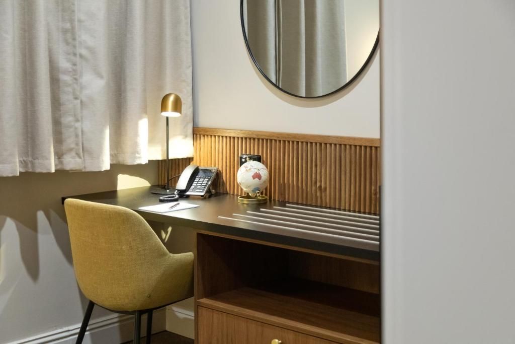 A hotel room with a desk, a telephone, a globe, and a mirror.