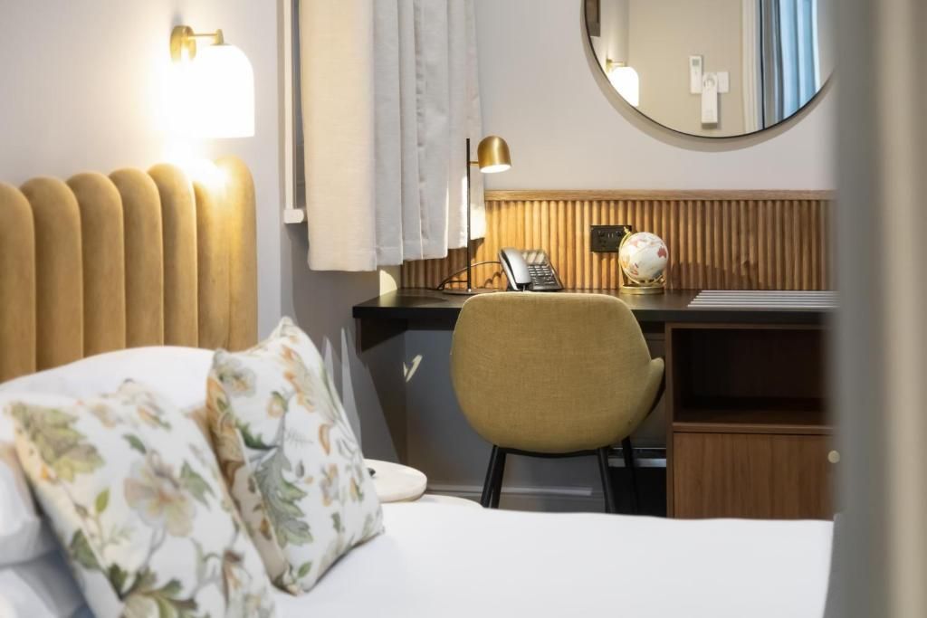 A hotel room with a bed, a desk, a chair, a globe, and a telephone.