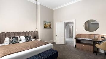 A bedroom with a bed, bedside table, chair, desk, and a mirror.