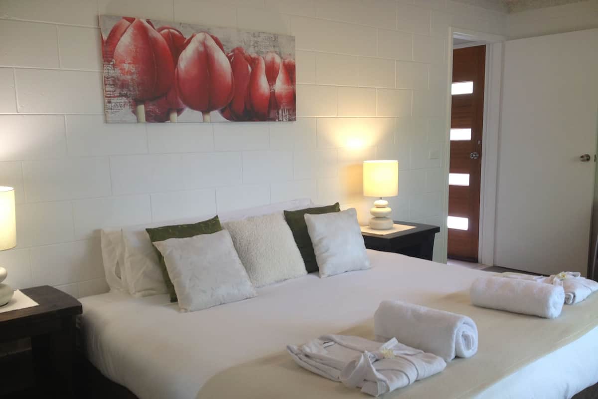 A neatly made bed with white linens, two pillows, and a folded towel on the bed.