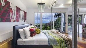 Een moderne slaapkamer met een groot bed, uitzicht op de omgeving en een bijzondere plafondlamp.
