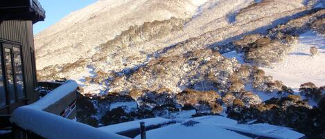 A mountain landscape with snow-covered slopes and a wooden building with a snow-covered roof.