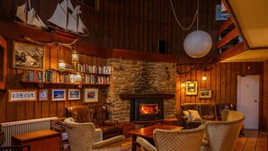 A cozy room with a fireplace, bookshelves, and comfortable seating. - Kasees Apartments & Mountain Lodge (Thredbo)