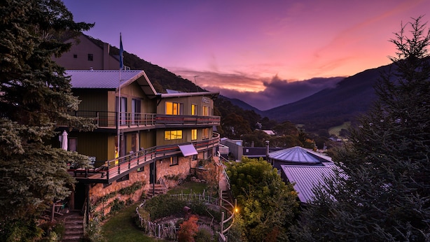 A two-story house with a balcony, surrounded by trees and a mountain backdrop. - Kasees Apartments & Mountain Lodge (Thredbo)