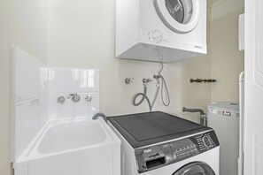 A laundry area with a washing machine, a dryer, and a bathtub. - Trinity Beach Retreat (TRINITY BEACH)