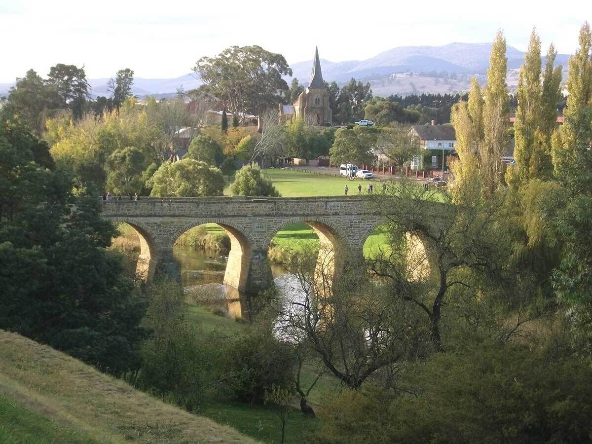 A stone bridge over a river with a church in the background.