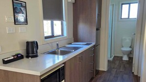 A compact kitchen with a built-in microwave, a coffee maker, and a sink. - BIG4 Hobart Airport Tourist Park (Cambridge)