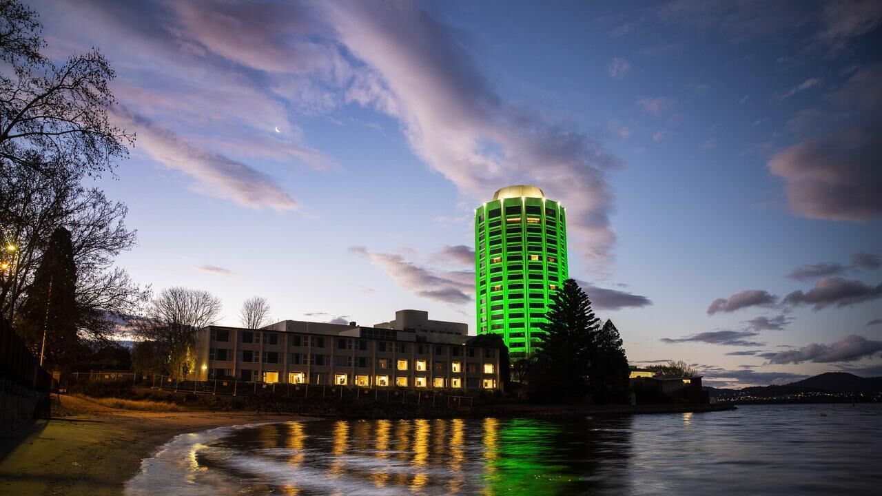 A hotel with a modern design, a waterfront view, and a reflection on the water.