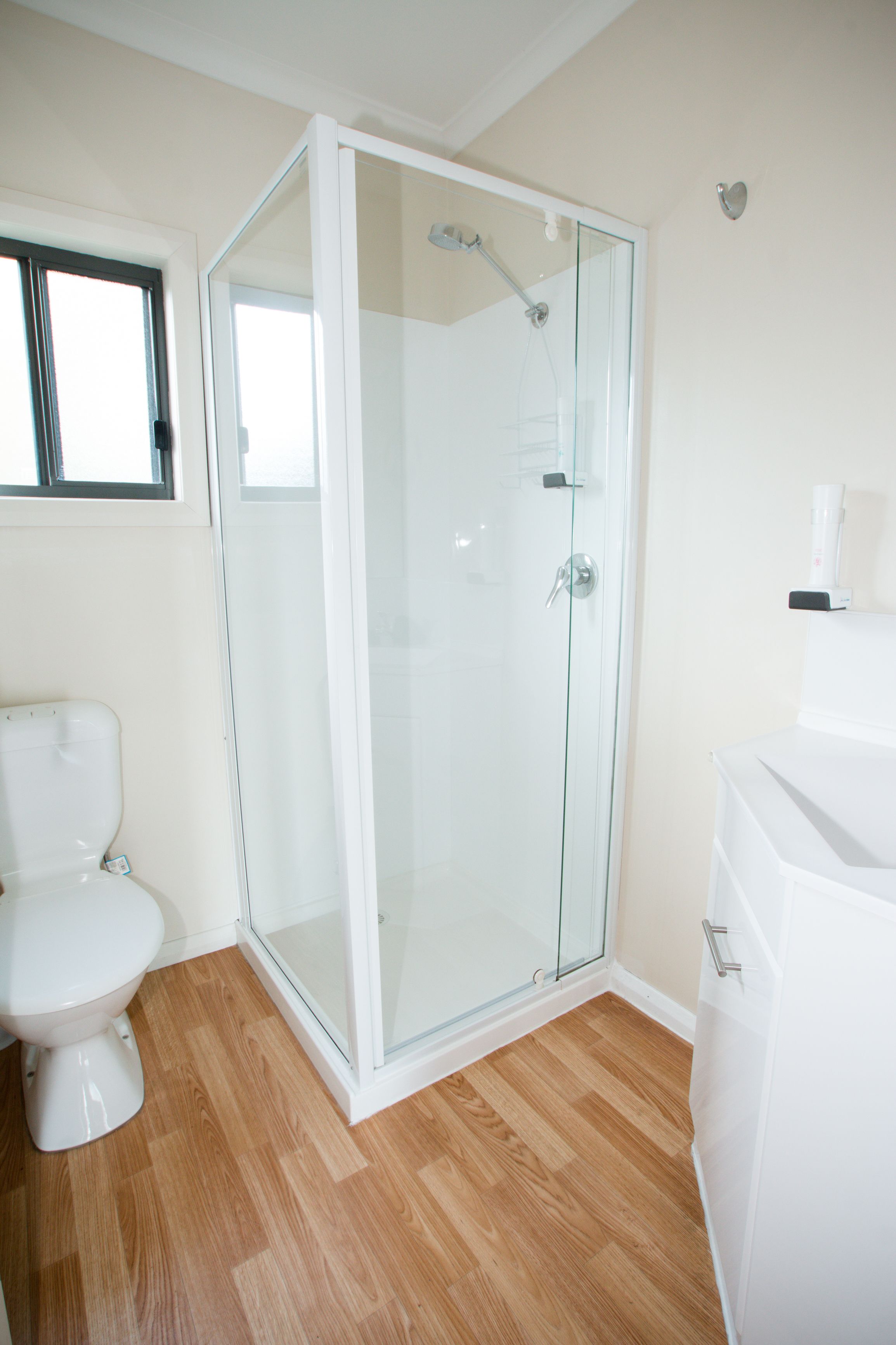 A bathroom with a glass-enclosed shower, a toilet, and a sink.