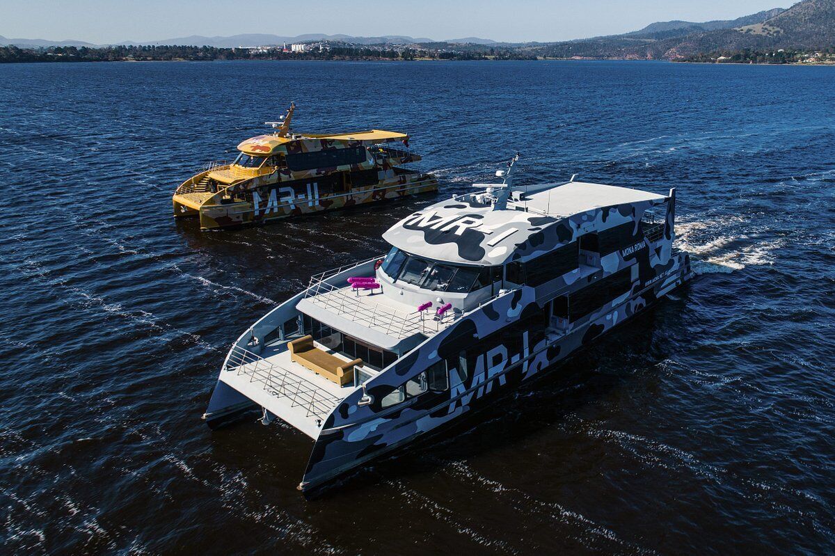 Dos barcos en un cuerpo de agua con un paisaje montañoso al fondo.