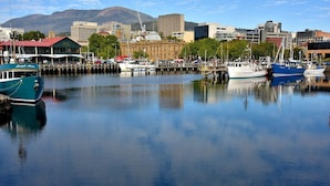 A marina with boats docked, a building with a red roof, and a mountain in the background. - BIG4 Hobart Airport Tourist Park (Cambridge)