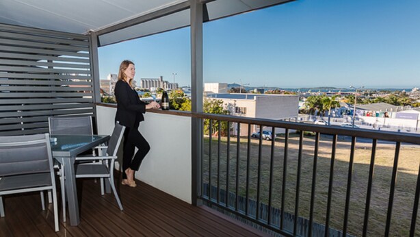 Un balcon donnant sur le paysage urbain, une table avec des chaises et une bouteille de vin.