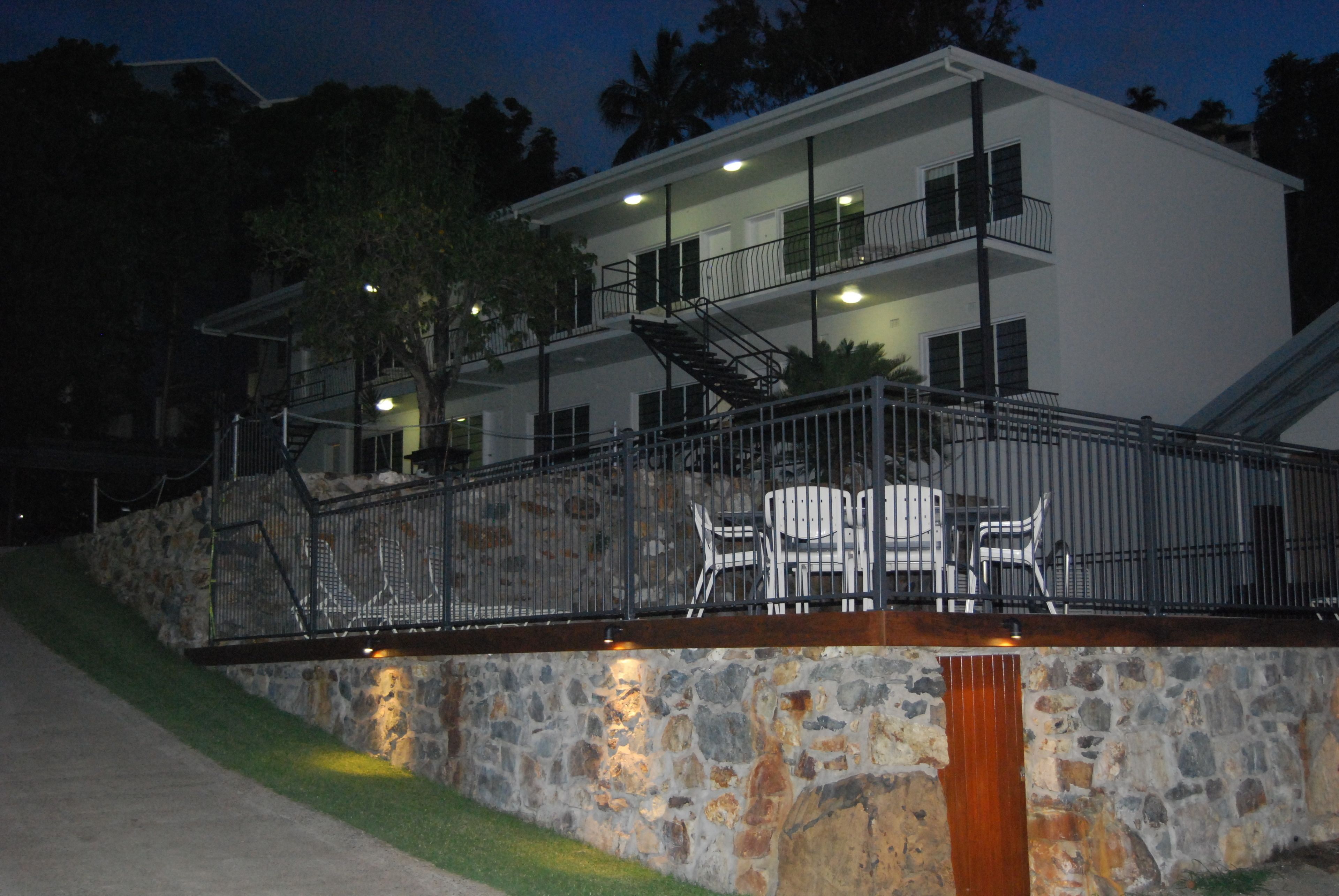Un bâtiment à deux étages doté d’une façade en pierre, d’un balcon avec des chaises et d’un escalier.