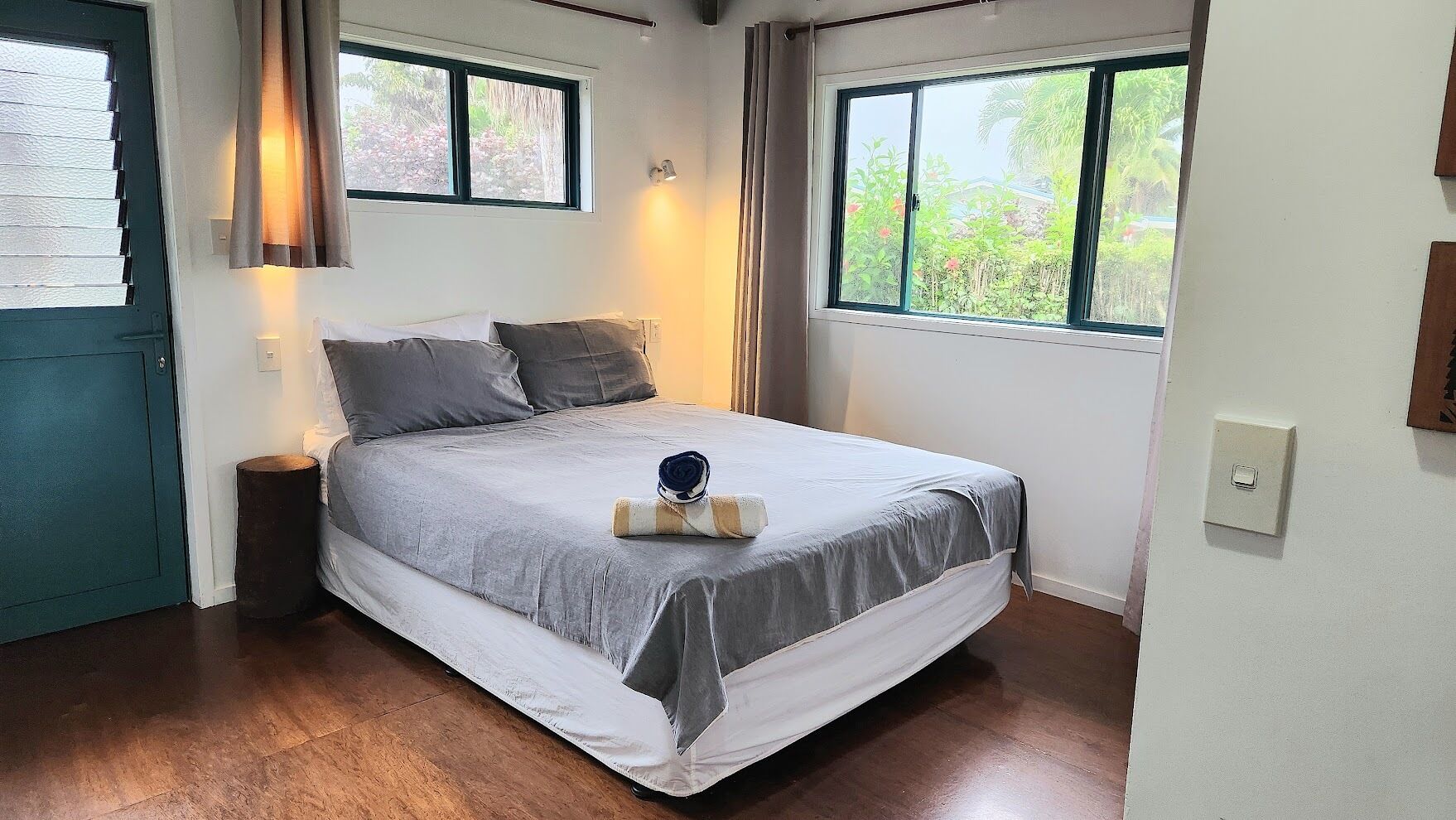 A bedroom with a bed, a nightstand, a window, and a door.