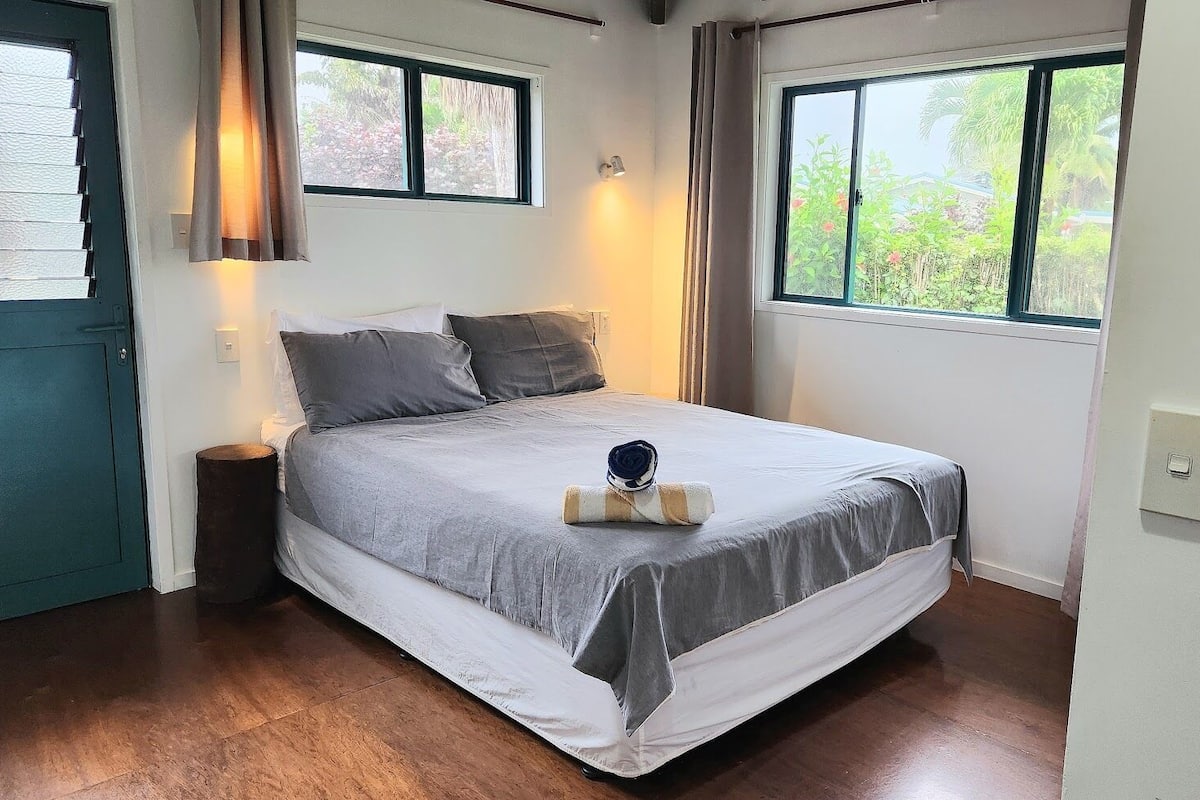 A bedroom with a bed, a nightstand, a window, and a door.