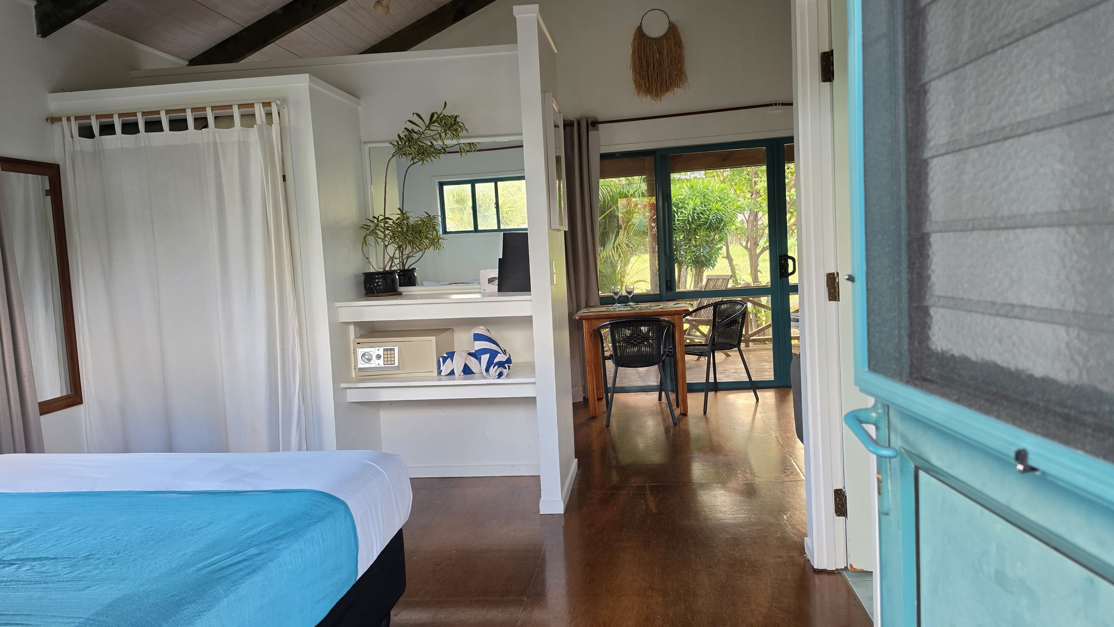 A room with a bed, a desk, and a view of the outdoors.