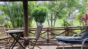 A wooden deck with outdoor furniture, including a table and chairs, overlooking a lush garden with various plants and trees.