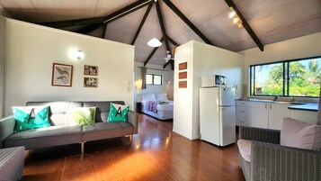 Un interior moderno con sofá, cama, kitchenette y vistas por una ventana.