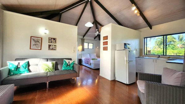 Un interior moderno con sofá, cama, kitchenette y vistas por una ventana.