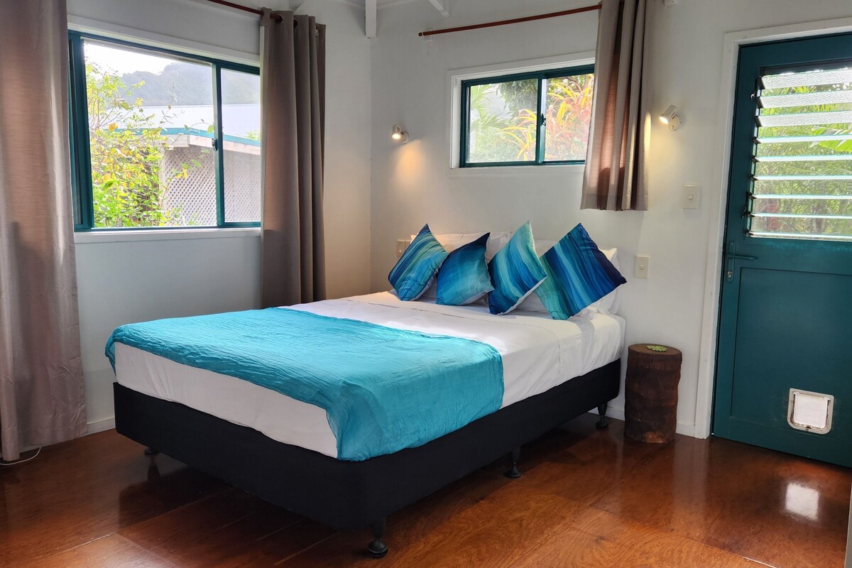 A bedroom with a bed, curtains, windows, and a door.