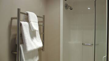 A bathroom with a glass shower enclosure and a towel rack with two white towels.