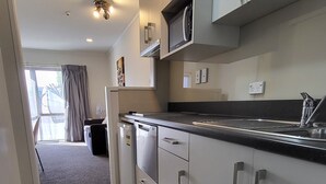 A modern kitchen with grey cabinets, a black countertop, and a built-in oven. - Manukau Motor Lodge (Auckland)