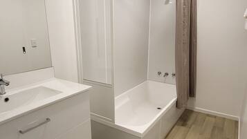 Un baño moderno con un tocador blanco, una bañera y una ducha.