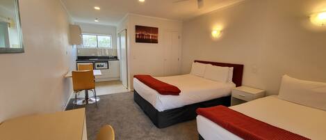 Une chambre d’hôtel équipée d’un lit, d’un bureau, d’une chaise et d’une kitchenette.