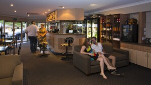 A bar area with a counter, seating, and a wine display. - James Street Motor Inn (South Toowoomba)
