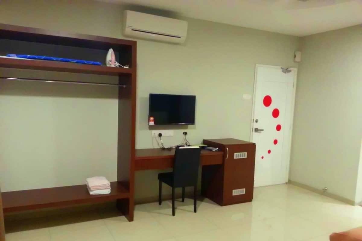 A room with a bunk bed, a desk with a chair, a television, and a door with red dots.