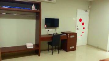 A room with a bunk bed, a desk with a chair, a television, and a door with red dots.